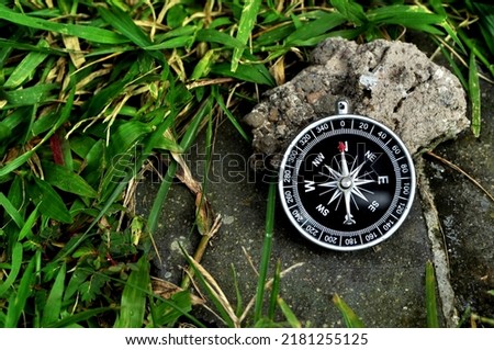 Navigation compass in ground with green grass