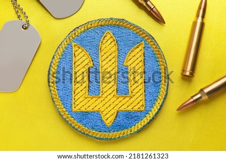 Flat lay composition with Ukrainian army chevron, military ID tags and bullets on yellow background