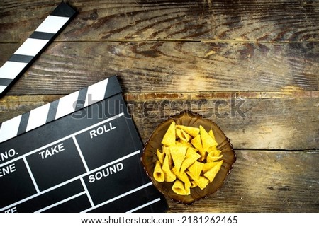 clapper board of video cinema in studio, cone corn chips in glass bowl on wooden table
