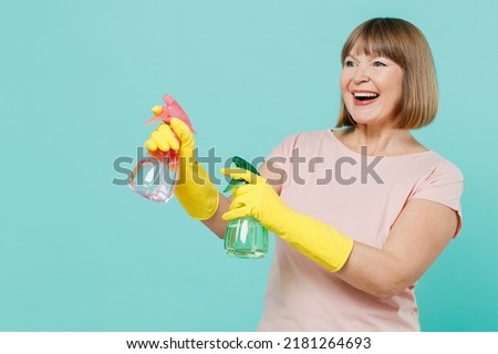 Elderly housewife woman 50s wear pink t-shirt gloves hold use basin detergent chemical bottles washing cleansers isolated on plain pastel light blue background Housekeeping cleaning tidying up concept