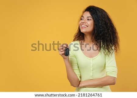 Beautiful happy satisfied joyful african american young woman 20s wears green shirt hold key ring looking aside away isolated on yellow background studio portrait. People emotions lifestyle concept. Royalty-Free Stock Photo #2181264761