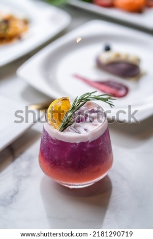 lychee and butterfly pea mock-tail with orange and rosemary garnish Royalty-Free Stock Photo #2181290719