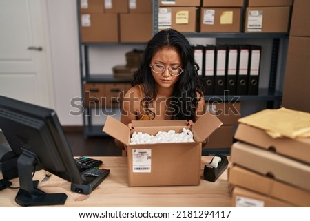 Young asian woman working at small business ecommerce skeptic and nervous, frowning upset because of problem. negative person. 