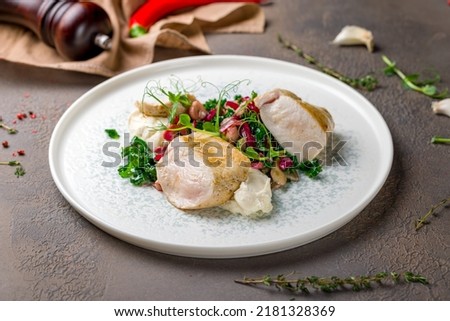 Sliced Grilled chicken Breasts with garnish on plate on brown table