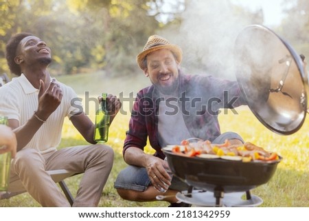 Two guys are preparing a barbecue for friends. The joy of grilling together in nature.