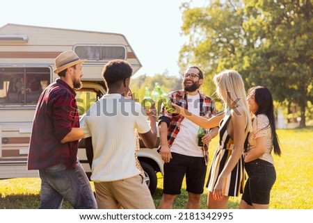 A group of cheerful friends set off on an RV trip. The students have arrived at their destination and are enjoying their time together. They are drinking beer and laughing