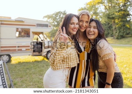 Smiling student girls spend time together traveling in their beloved old camper van.