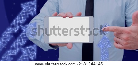 Businessman Holding A Touch Screen And Pointing On A Jigsaw With Abstract Arrows Design. Man In A Necktie Working On Computer Applications And Digital Information.