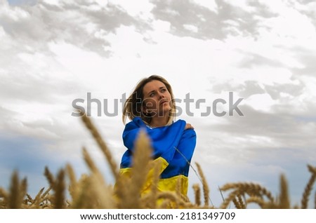 Girl in a wheat field.A girl with a Ukrainian flag in a wheat field against the sky.Ukrainian girl in a wheat field.War in Ukraine. Ukrainian symbols.The concept of freedom.Arson of Ukrainian fields