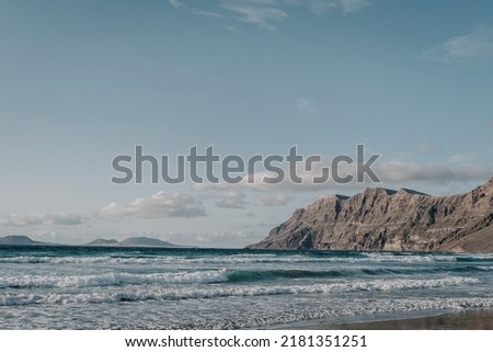 Tamara beach in Lanzarote with some cliffs and islands in the background