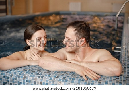 Cute couple talking and hugging near poolside in indoors swimming pool