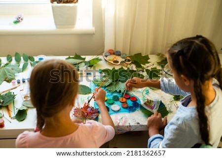 two schoolgirls draw leaves, girls paint autumn leaves