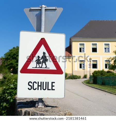   Danger sign indicating possible school children in the road area in the municipality of Emmersdorf in Austria. Translation on the sign: School                              