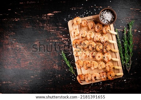 Delicious grilled shrimp on a cutting board with rosemary and spices. On a rustic dark background. High quality photo