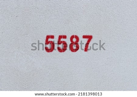 Red Number 5587 on the white wall. Spray paint.
