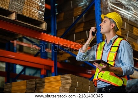 Handsome young man factory worker who are keeping a record of stock in a large warehouse. Export industry concept. Working at warehouse