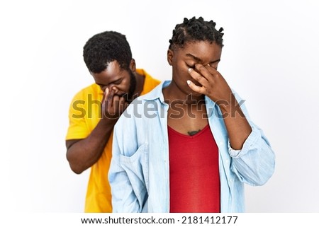 Young african american couple wearing casual clothes tired rubbing nose and eyes feeling fatigue and headache. stress and frustration concept. 