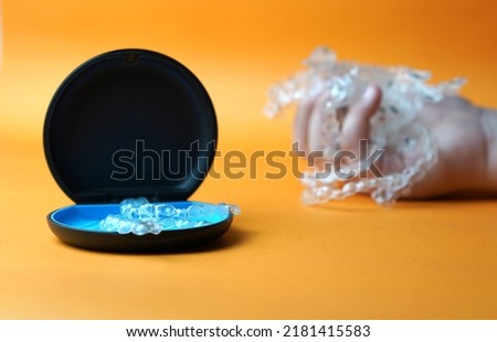 hand hold pile of invisible braces on case background
