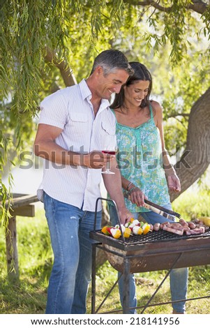 Couple Cooking Barbeque In Countryside