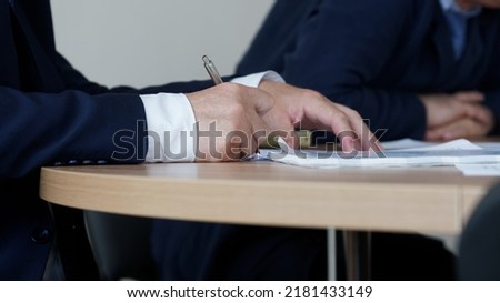 Man in an elegant suit signs or endorses a document during a working meeting or negotiations. No face. Clerk, official, deputy, politician, lawyer or businessman. Selective focus. Close-up