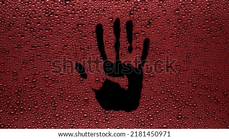 Handprint printed on the wet glass with red drops on black background | shower concept