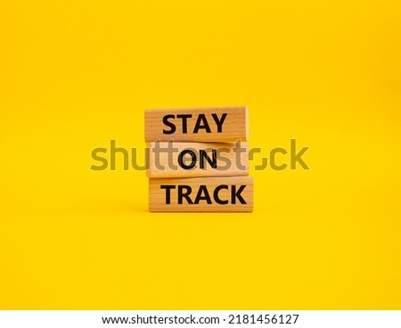 Stay on track symbol. Wooden blocks with words Stay on track. Beautiful yellow background. Businessman hand. Business and Stay on track concept. Copy space.