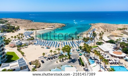 Aerial bird's eye view of Vathia Gonia beach, Ayia Napa, Famagusta, Cyprus.  Landmark tourist attraction rocky bay with golden sand, sunbeds, sea restaurants in Agia Napa on summer holidays from above Royalty-Free Stock Photo #2181457389