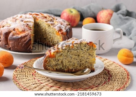 Homemade apricots pie with poppy seeds and apples, with cup of coffee on gray background