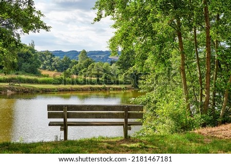 Relaxing lake or park bench to enjoy zen landscape view of scenic pond or bay of water in nature reserve or botanical garden. Local wooden seating or furniture in serene, tranquil or calm countryside Royalty-Free Stock Photo #2181467181