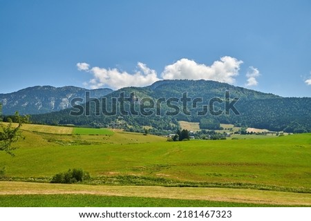 Farmland with lush meadow and hills or mountains covered with greenery in the countryside. Scenery of a calm empty field in nature. Natural view of open green landscape in the outdoors on a sunny day Royalty-Free Stock Photo #2181467323