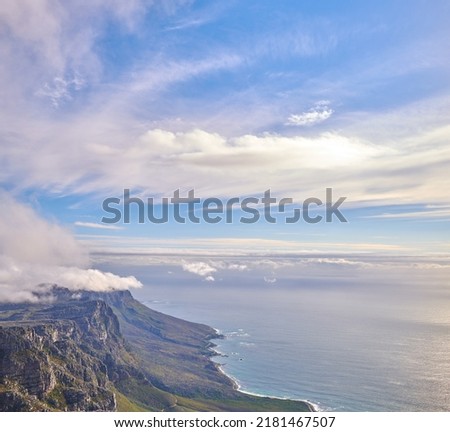 Panorama of a calm ocean and mountains with a cloudy blue cloudy sky background and copy space. Stunning nature landscape of the sea and horizon against The twelve apostles landmark in Cape Town