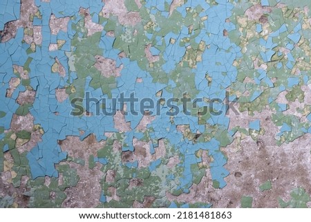 Peeling paint on the wall. Old concrete wall with cracked flaking paint. Weathered rough painted surface with patterns of cracks and peeling. Grunge texture for background and design. High resolution.