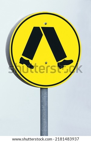 Australian Pedestrian Crossing sign: black walking symbol on yellow background reminds drivers that they must give way to pedestrians at the road sections marked with a crossing. Brisbane-Queensland.