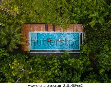 aerial drone view of swimming pool in the jungle of Krabi Thailand, aerial view with a drone above swimming pool in the jungle of Thailand. couple men and woman in pool from above Royalty-Free Stock Photo #2181489663