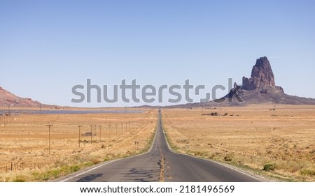 Scenic Road in the Dry Desert with Red Rocky Mountains in Background. Oljato-Monument Valley, Arizona, United States. Royalty-Free Stock Photo #2181496569