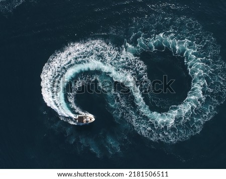 Aerial top view of a white pleasure boat on a summer day. Powerboat turn loop eight on the sea making infinity future concept.  Royalty-Free Stock Photo #2181506511