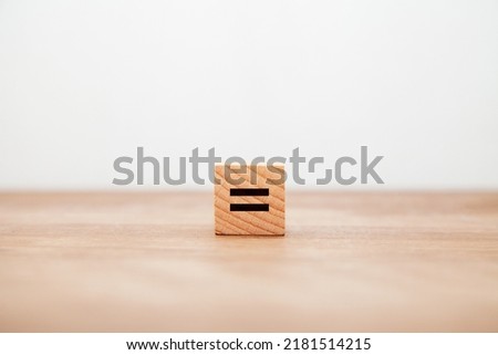 = Symbol. equal. equal. same. Written on a wooden block. White letters. Wooden table background.