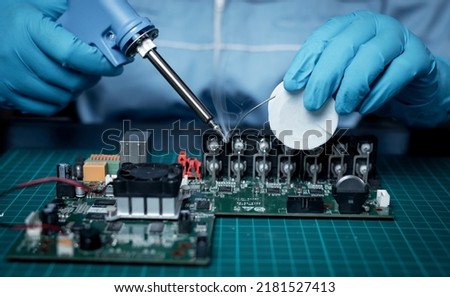 Technician under fixed digital video recorded CCTV board process by used tin soldering iron on chip is electronic component concept. Royalty-Free Stock Photo #2181527413