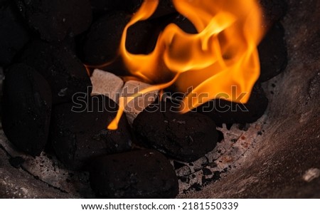 Lighting a barbecue fire. Briquette and white cube grill lighter. Flame with charcoal.
