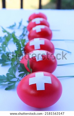 The eggs are painted like the flag of Switzerland: red with white crosses. In contrast, the greens of parsley go well with the eggs. Composition for Swiss National Day.  