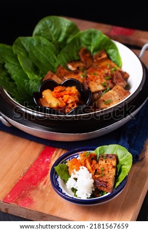 Asian food concept homemade Korean Grilled pork belly BBQ Samgyeopsal-gui with kimchi and shiso and salad on black background with copy space Royalty-Free Stock Photo #2181567659