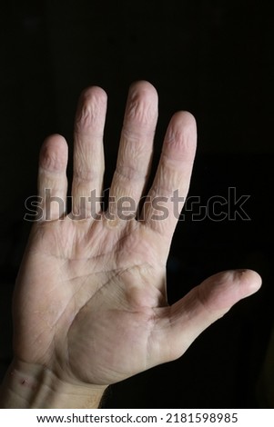 Skin wrinkling while bathing. male hands on a black background. water wrinkles on the fingers
