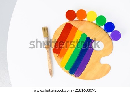 palette and paints with LGBT flag on white table