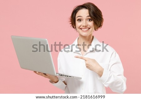 Happy young successful employee business woman corporate lawyer in classic formal white shirt work in office point index finger on laptop pc computer isolated on pastel pink background studio portrait