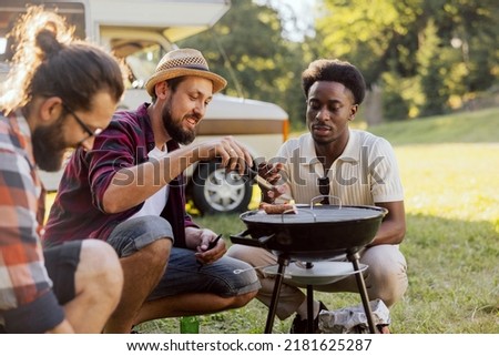 A bearded middle-aged guy is preparing a barbecue for friends. A group of college guys hang out together. RV trip