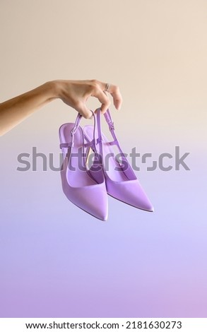 A hand holds fashionable purple women's shoes.light background. fashion shoes Royalty-Free Stock Photo #2181630273