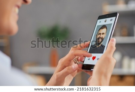 Smiling woman giving like to photo on social media or swiping on online dating app. Close up finger pushing heart icon on screen in smartphone application. Online dating concept.