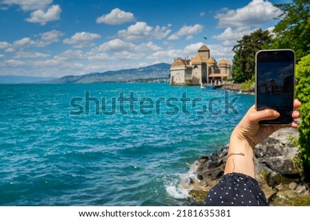 A girl takes a picture of Chillon Castle in Montreux, Switzerland