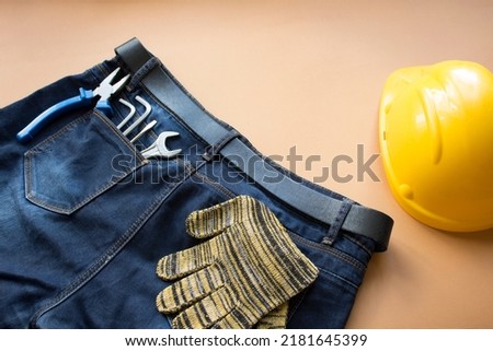 Working tool in the pocket of blue jeans on a neutral background
