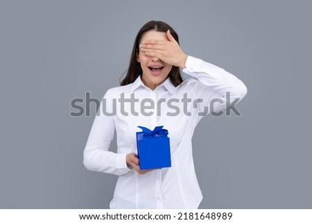 Portrait of a happy girl with gift box isolated over gray background. Woman holding gift present.